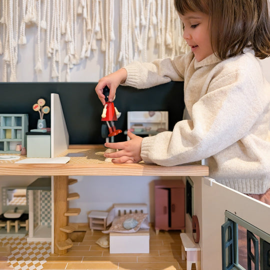 Child playing with a toy in a dollhouse setup
