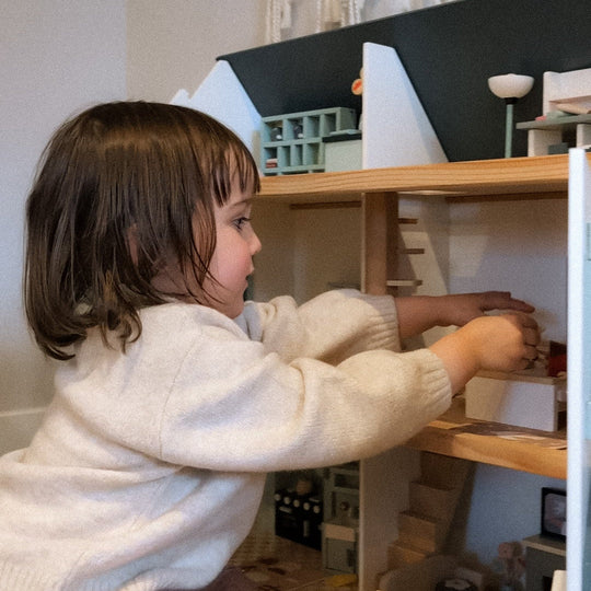 Child playing with a toy dollhouse
