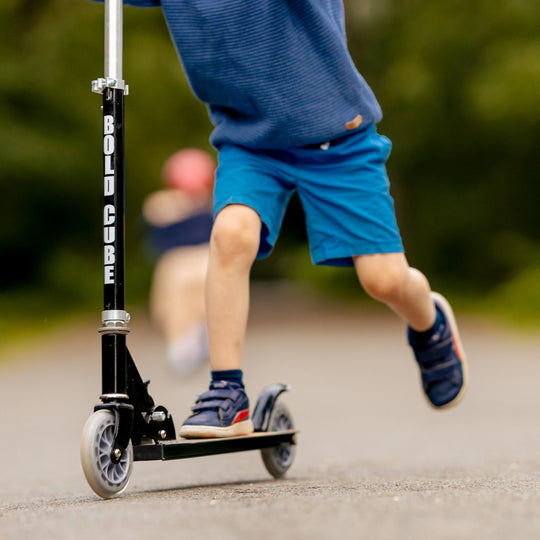 Child riding a scooter with 'Bold Cube' branding on a blurred background