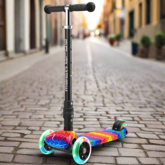 Children's three wheeled scooter with black handles and vertical bar with 'Bold Cube' written down it, and a colourful rainbow tread and colourful light-up wheels