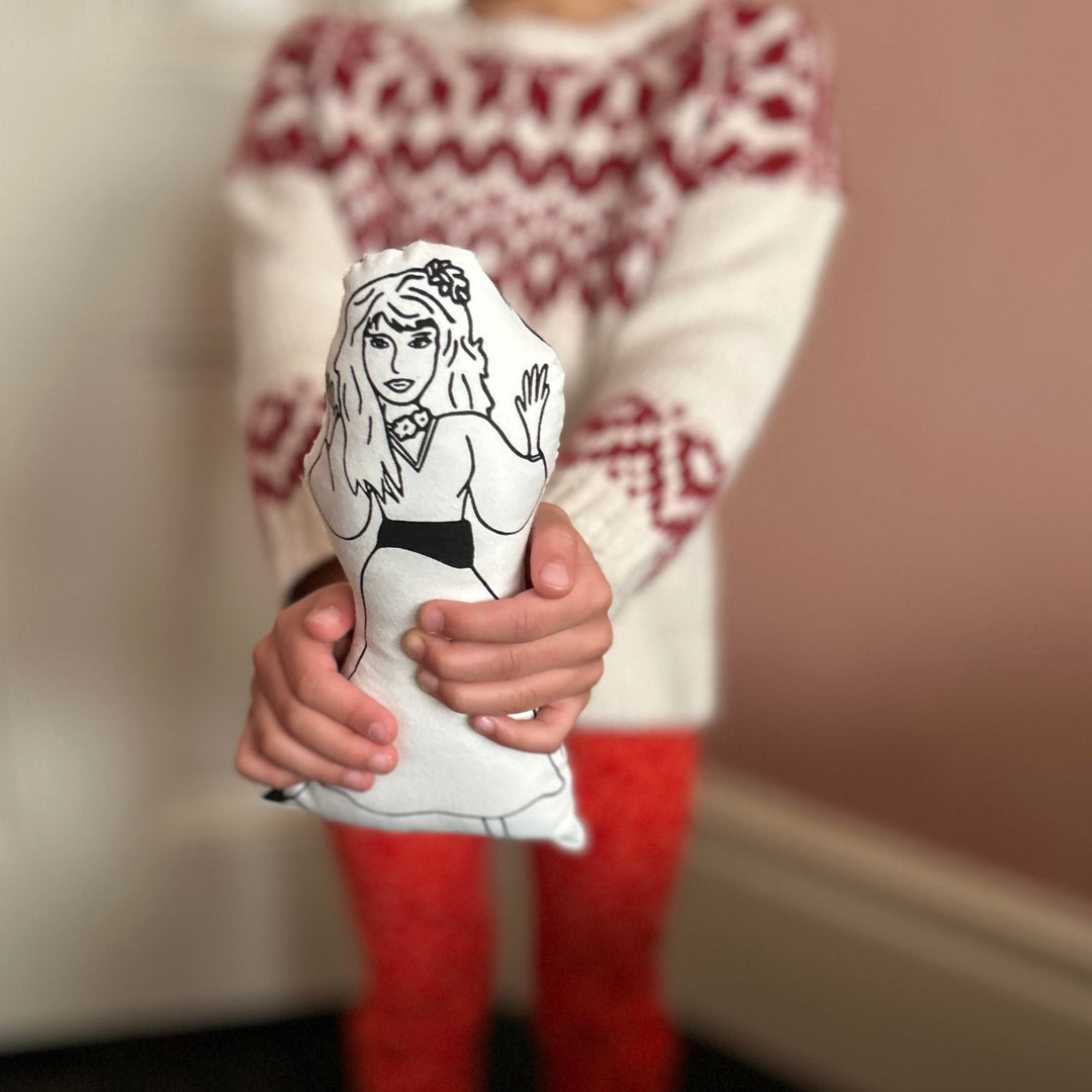 A child holding out screen printed doll cushion of singer Kate Bush
