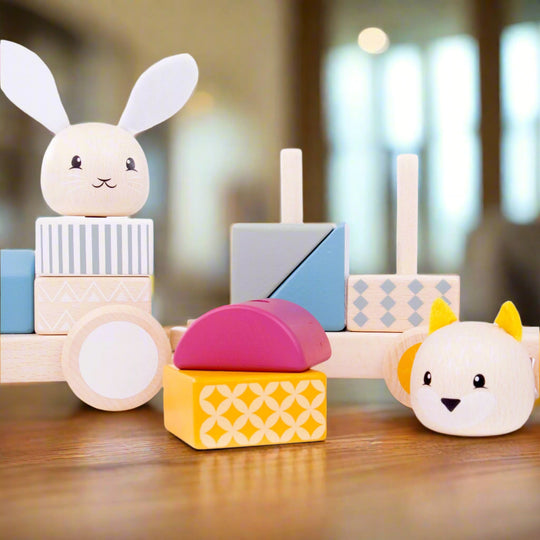 Close up of pull along toy train parts dismantled, with two colourful blocks and animal heads taken off the train and sitting next to it