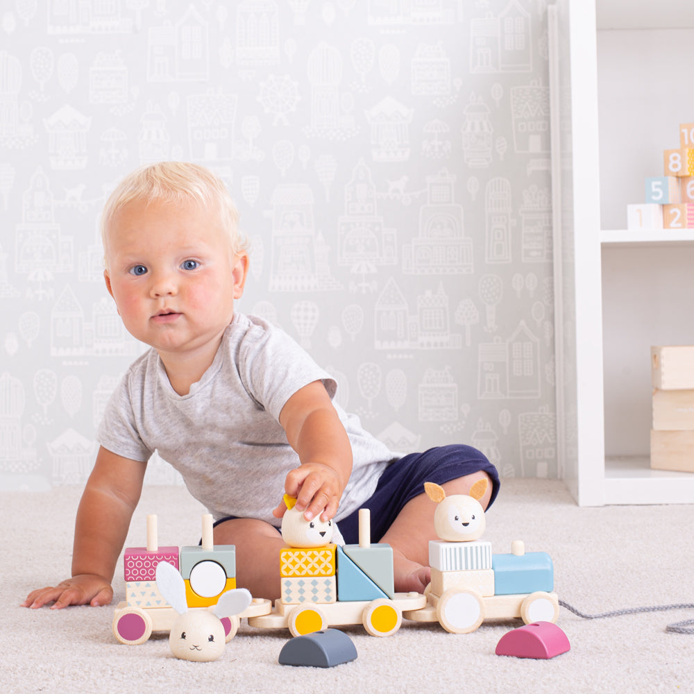 A toddler playing with the toy train, stacking parts onto it