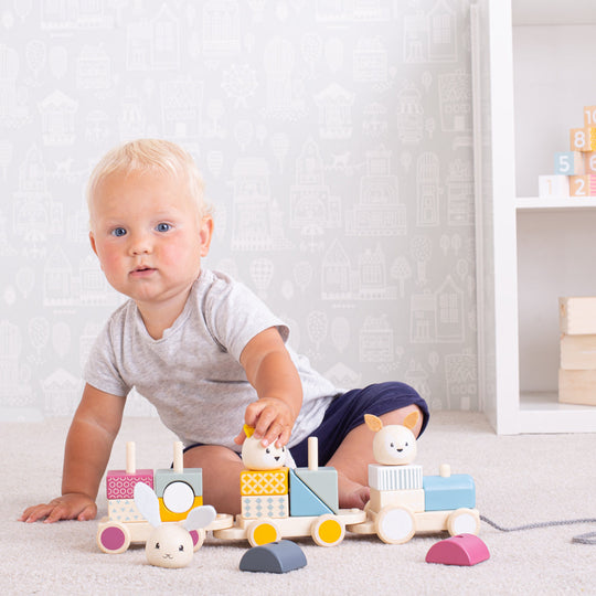 A toddler playing with the toy train, stacking parts onto it