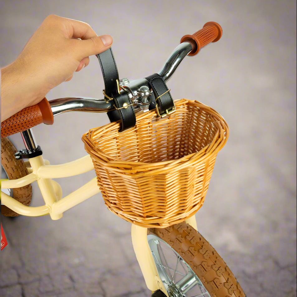 Close up of basket again with a person's hand undoing the leather straps that are attaching the basket onto the handlebar