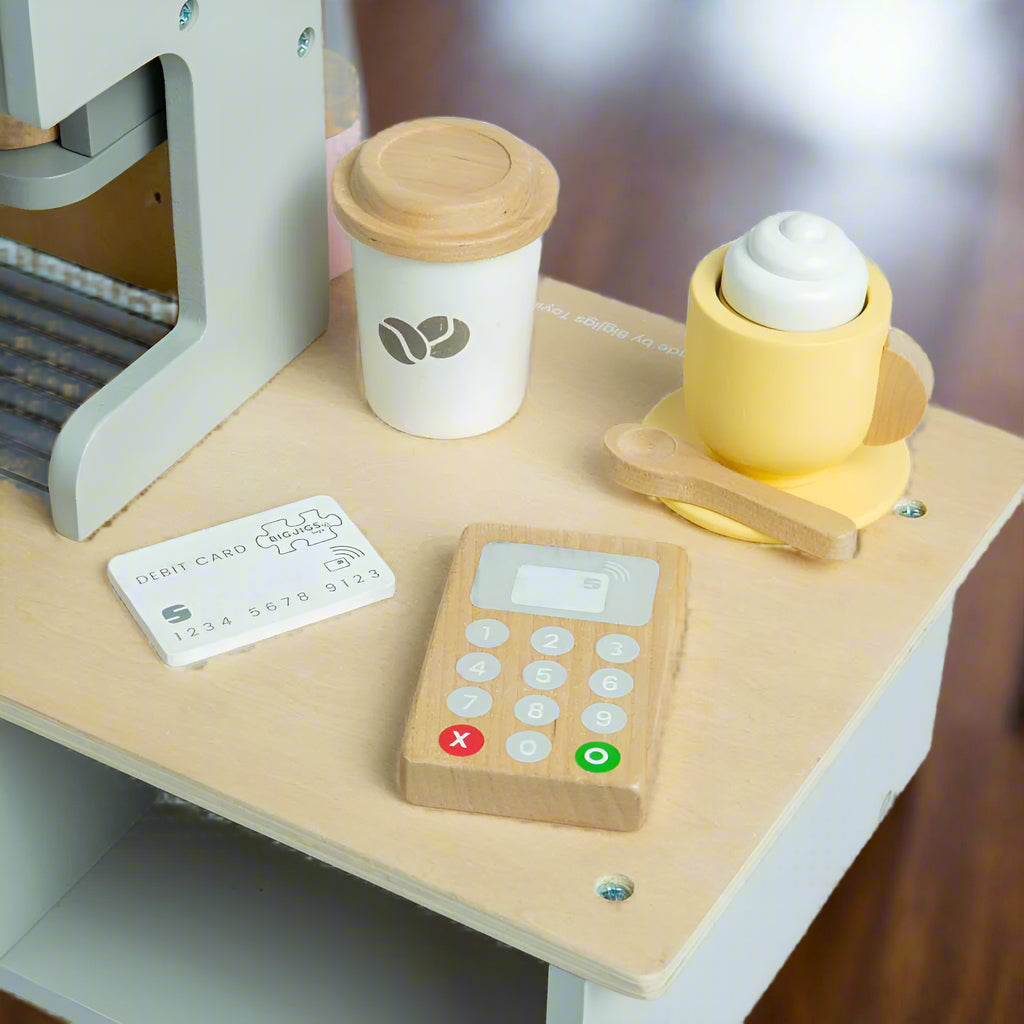 Close up of wooden card machine with a wooden debit card and two play coffees