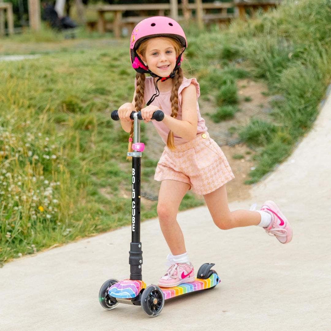 Child riding a scooter with a helmet on a path outdoors