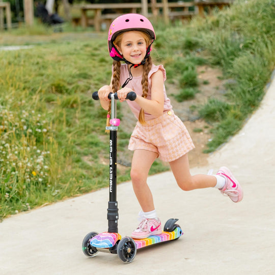 Child riding a scooter with a helmet on a path outdoors