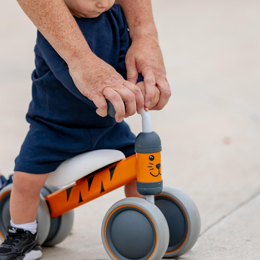 Child using a balance bike with a tiger design on a light background
