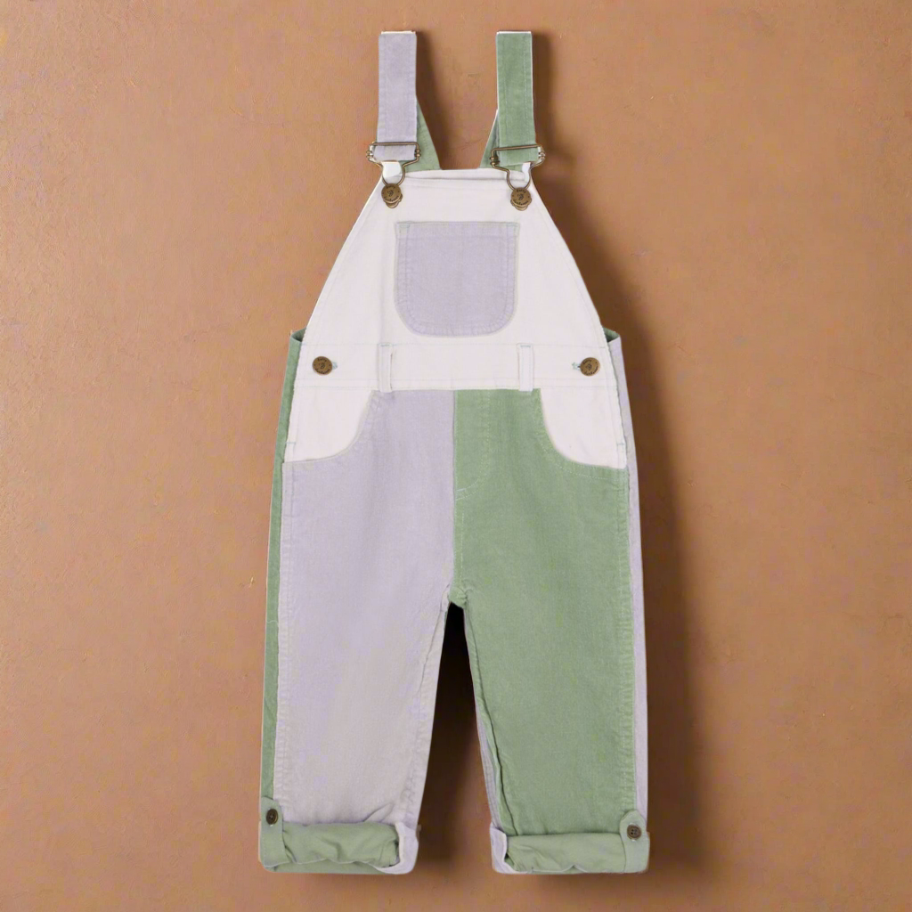 Corduroy dungrees with patchwork blocks of white, pale lilac and sage green, with two side pockets and a central chest pocket with brass buttons