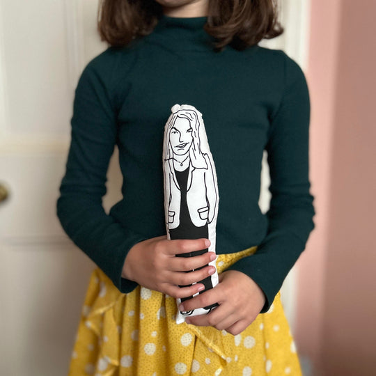 A child holding a black and white screen printed cushion doll with an illustration of artist Tracey Emin