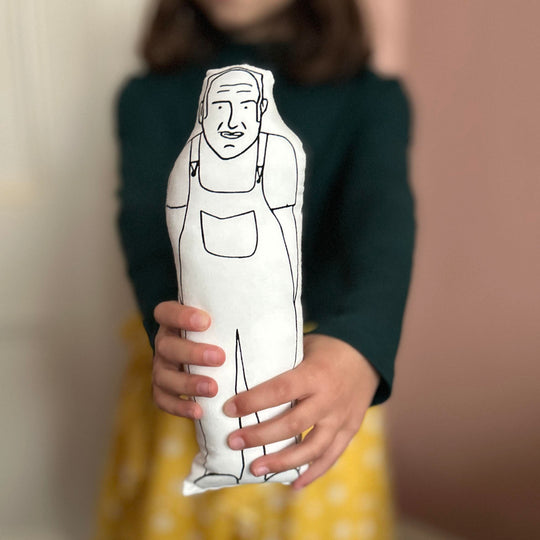 A child holding out a screen printed doll cushion of Keith Brymer Jones