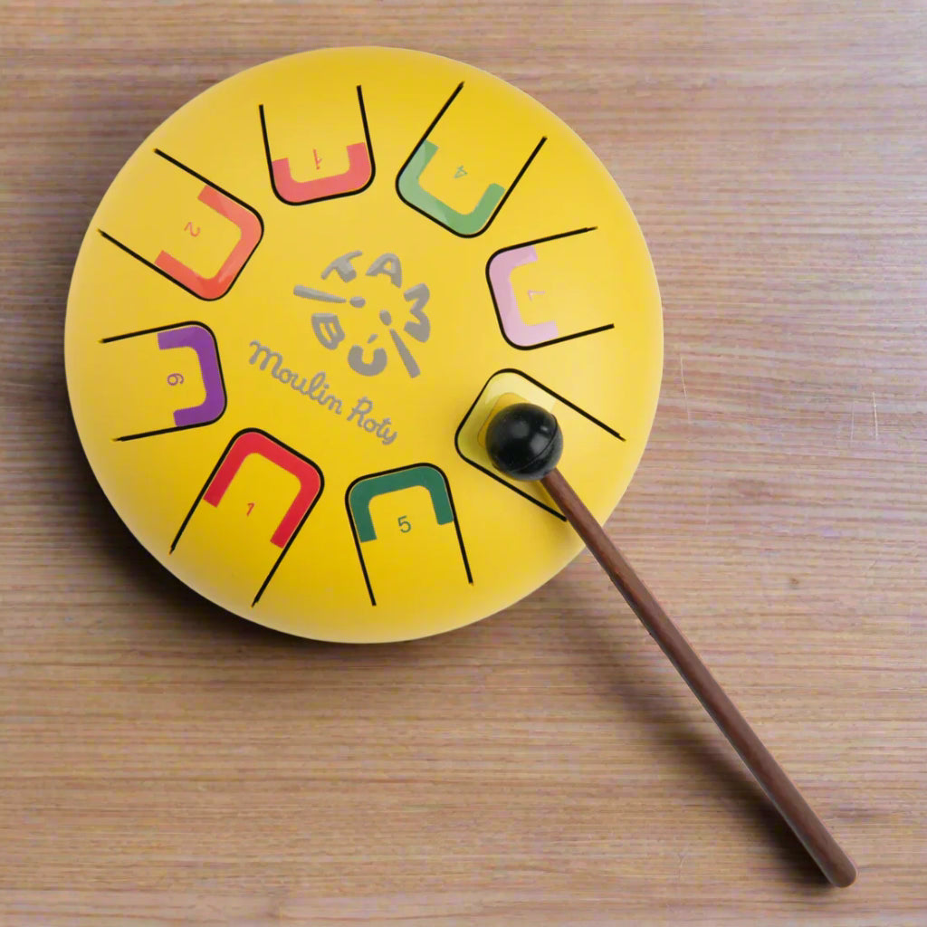 Yellow tongue drum instrument with colourful notes and a playing stick