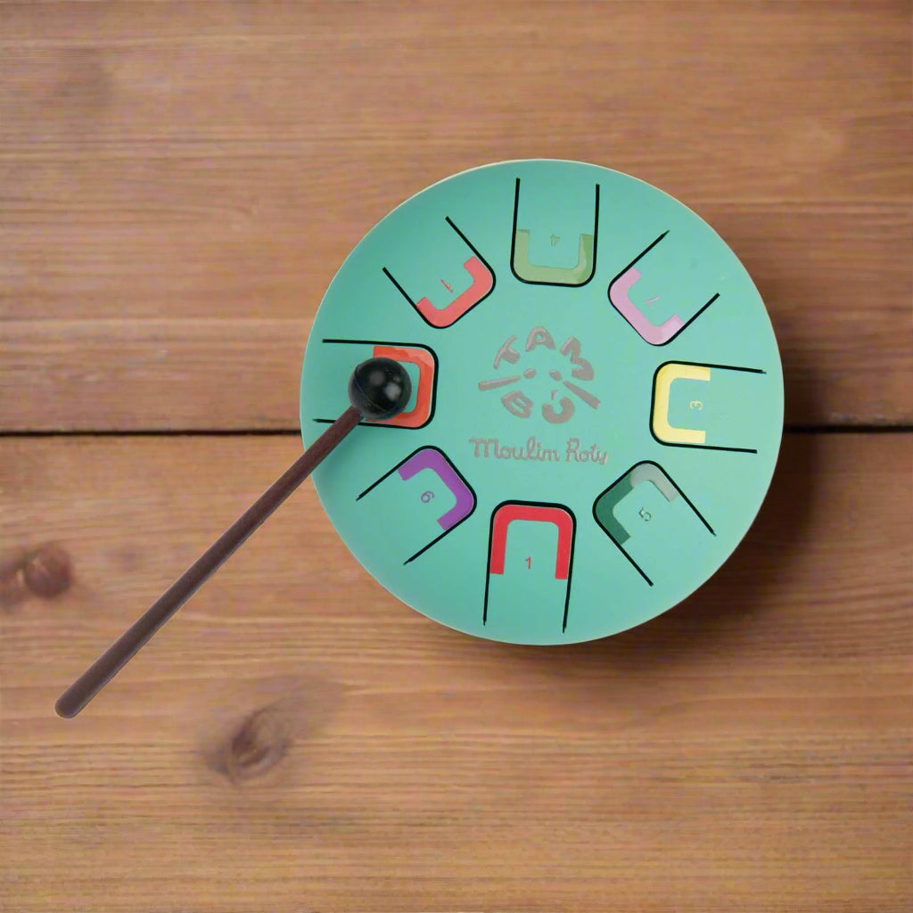 Teal coloured metal tongue drum instrument with colour-coded nots with a brown drumstick