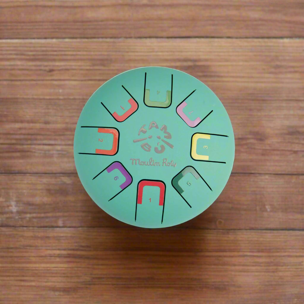 Teal coloured round metal tongue drum with colour-coded notes