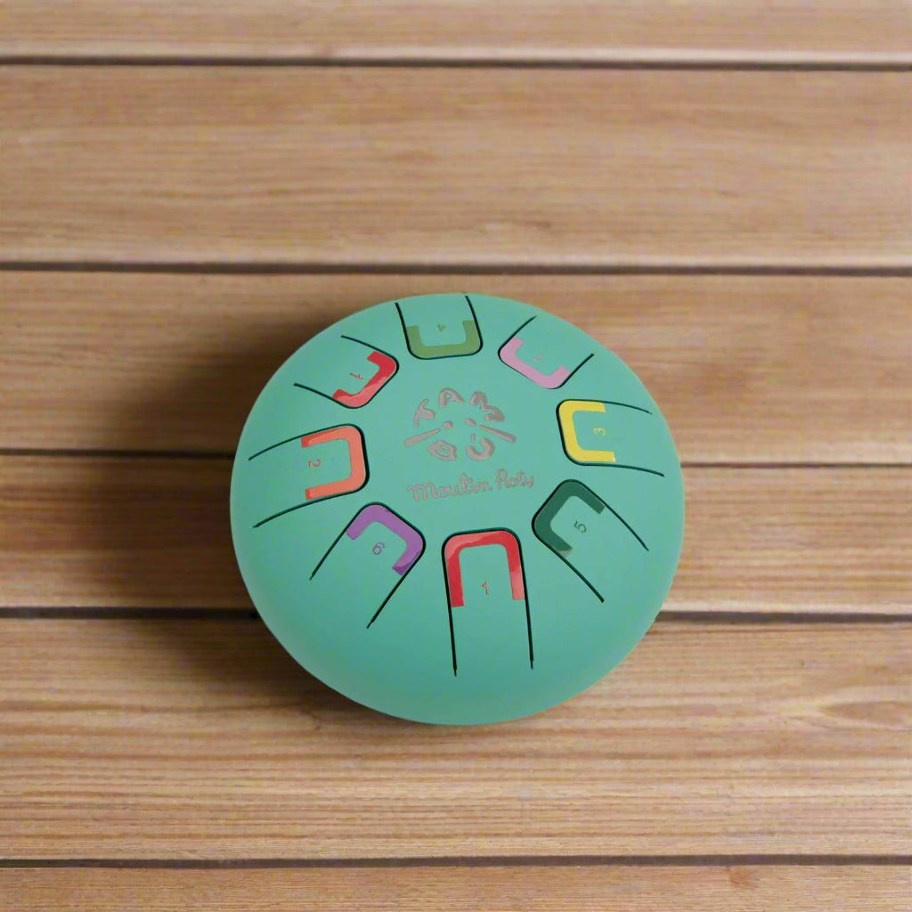 Round teal coloured metal tongue drum with colour-coded notes