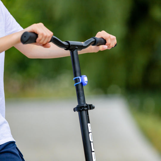 Close up of child's hands holding the handles of a scooter