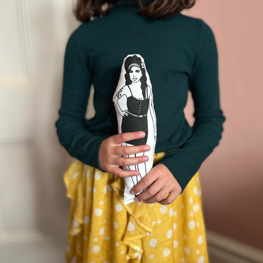 A child holding a screen printed doll cushion of singer songwriter Amy Winehouse