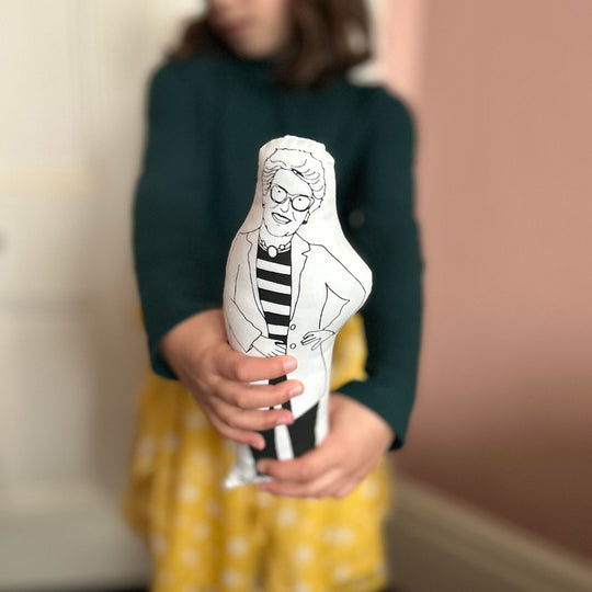 A child holding a black and white screen printed cushion doll depicting Prue Leith, suitable for fans of the Great British Bake Off