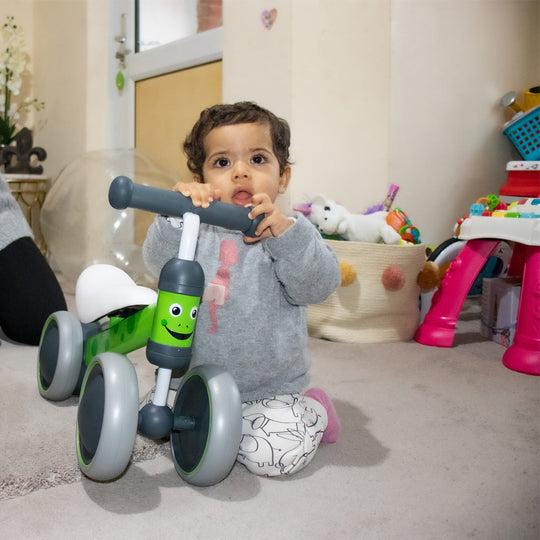 Child playing with a toy balance bike in a room with toys and furniture.