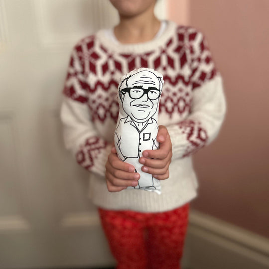 A child holding screen printed doll cushion of Danny DeVito