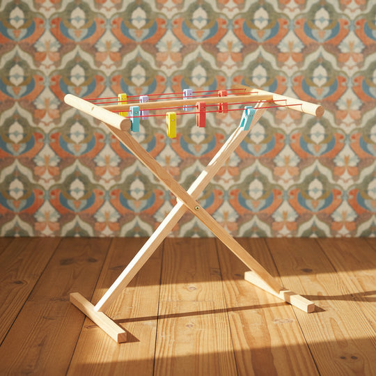 Children's wooden clothes airer with multicolored pegs designed for pretend play.