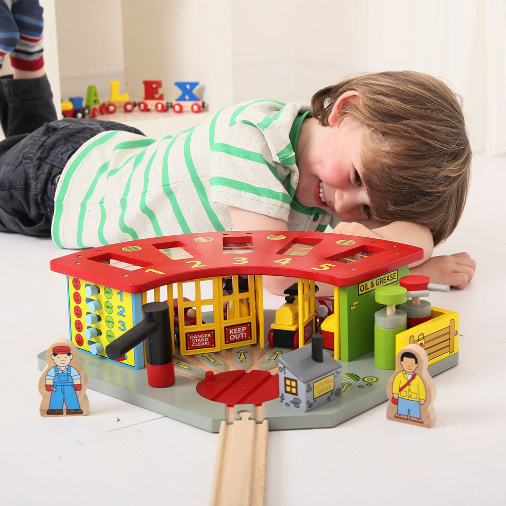 6-year-old child playing with wooden train enging shed