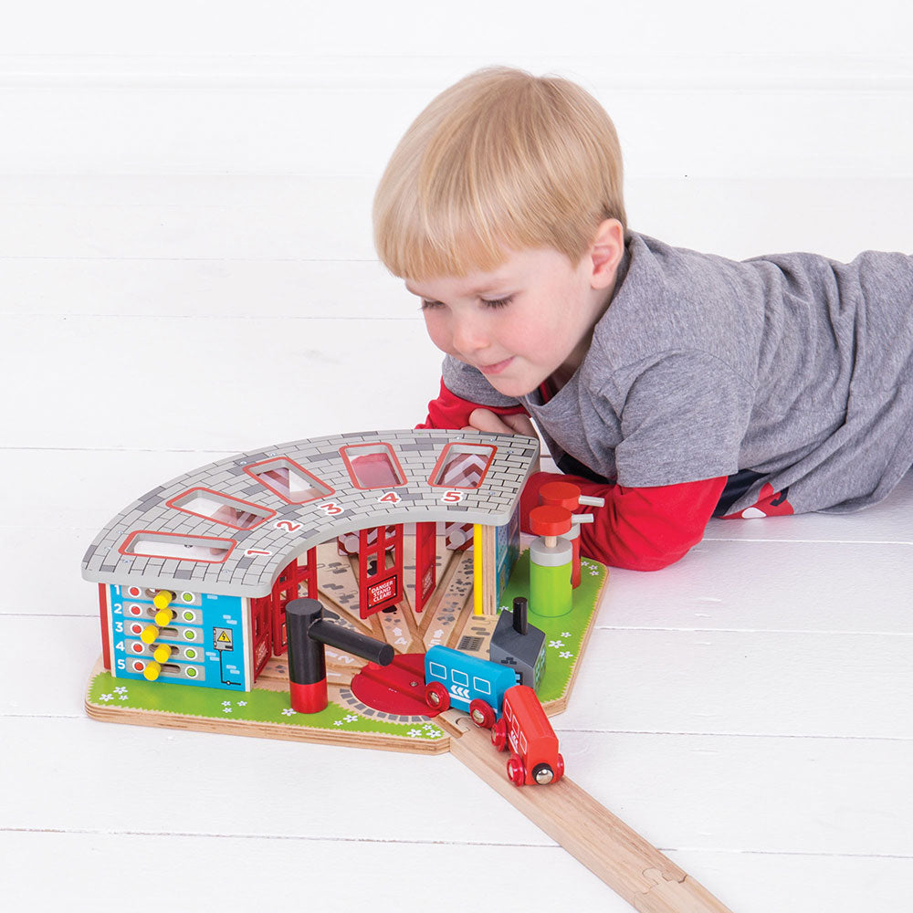 A different child of a similar age playing with the engine shed
