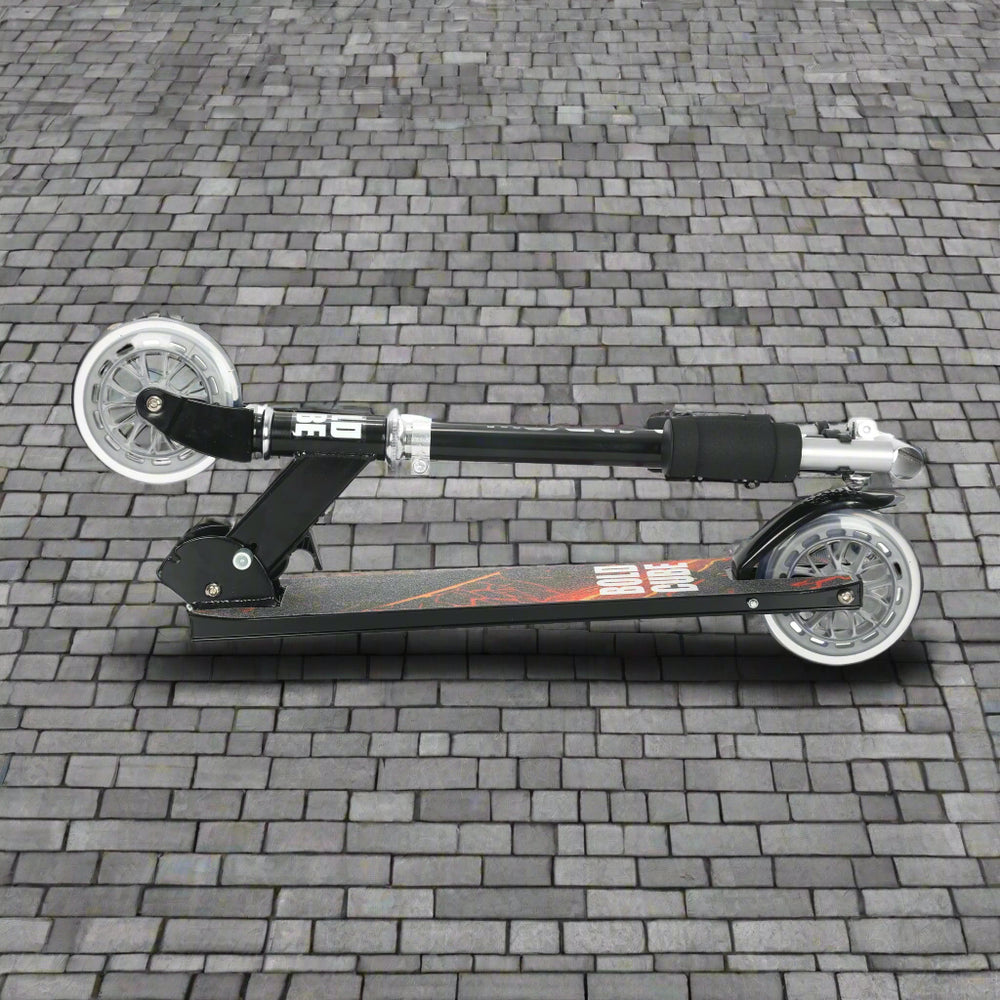 Black scooter folded into a portable size on cobbled paving