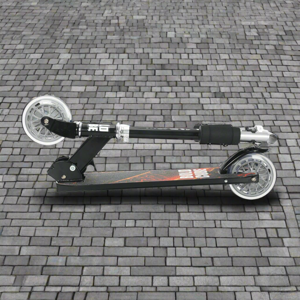 Black scooter folded into a portable size on cobbled paving