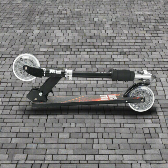 Black scooter folded into a portable size on cobbled paving