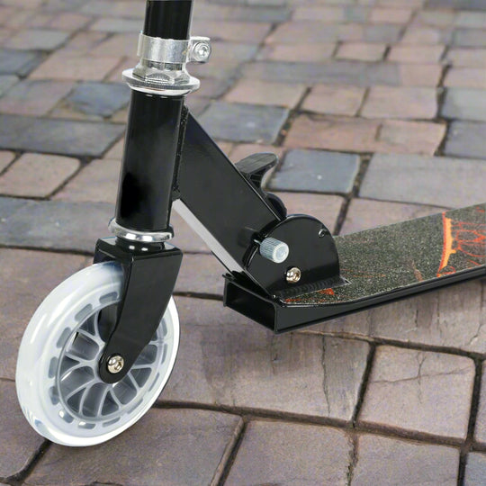 Close-up of a scooter with a black deck and white wheel on a cobbled paving background