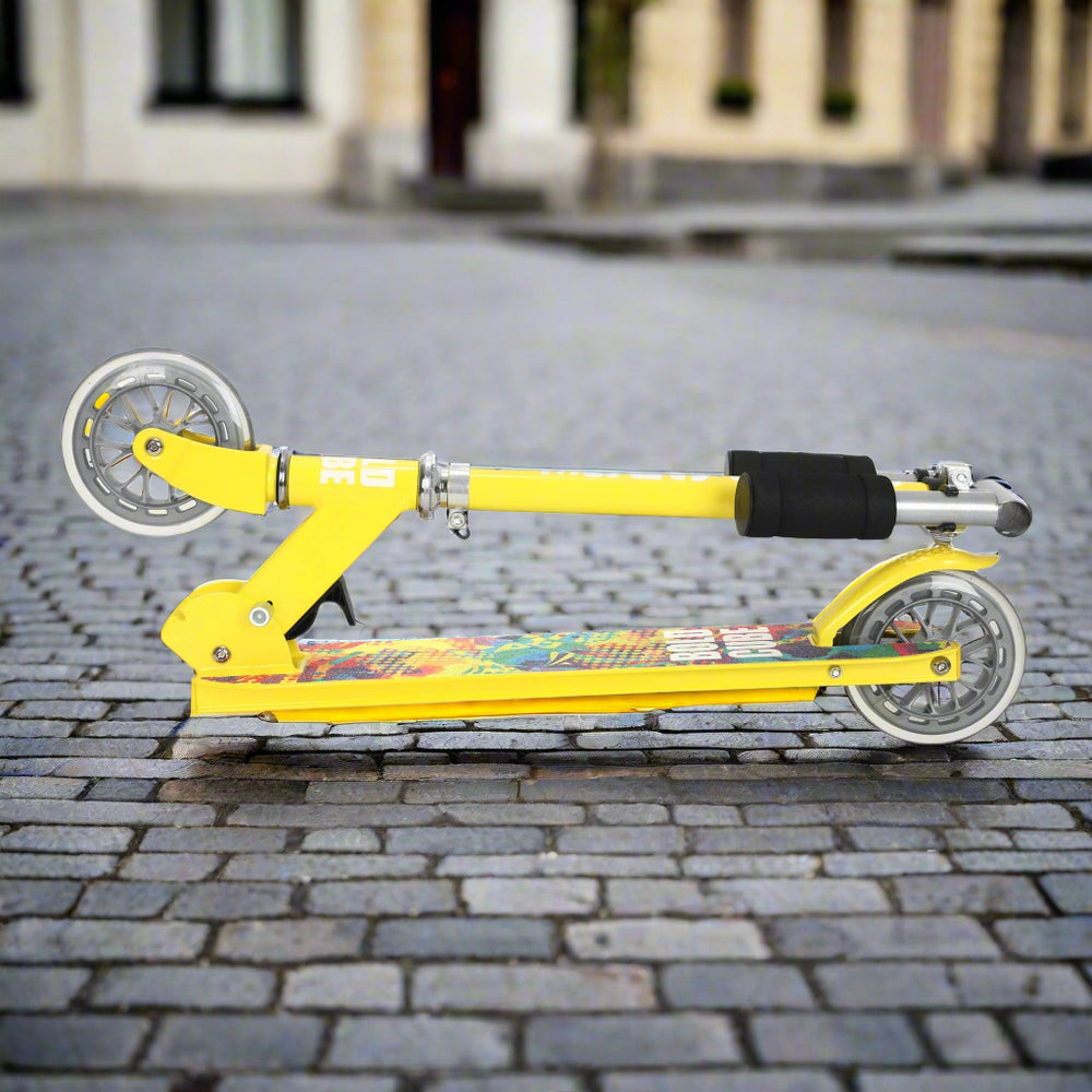 Yellow scooter folded into a portable size on a cobbled pavement background