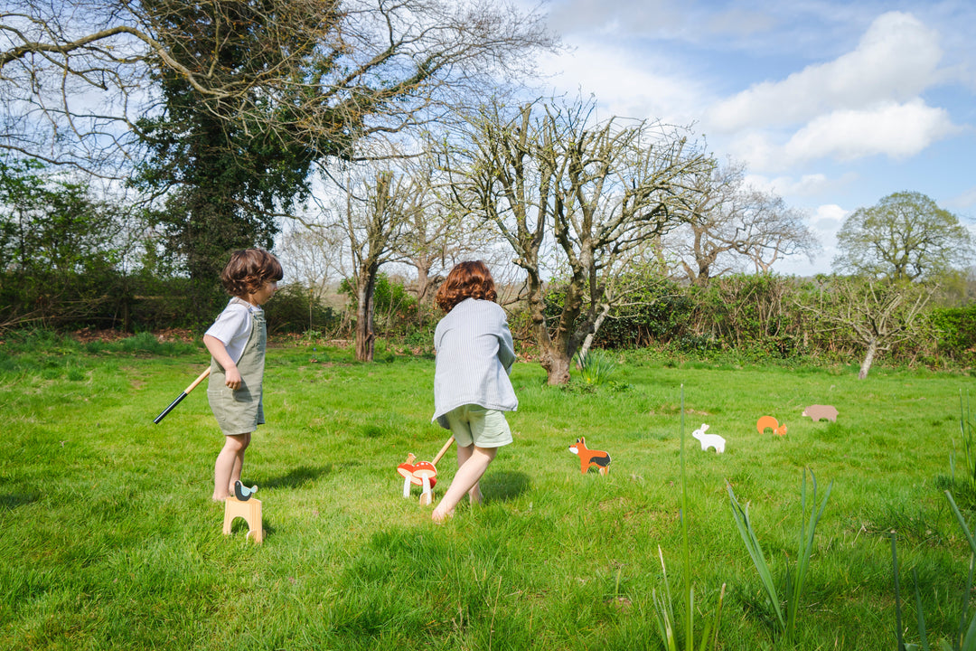 Two children playing with toys in a grassy field on a sunny day.