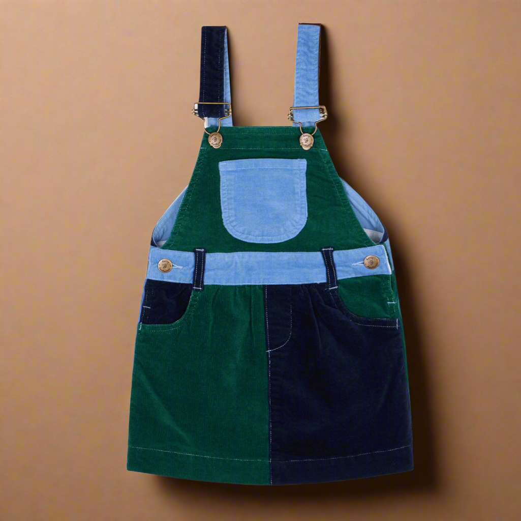Corduroy dress with blocks of different colours, pale blue, dark green and dark blue, with two side pockets and a central chest pocket, and brass buttons
