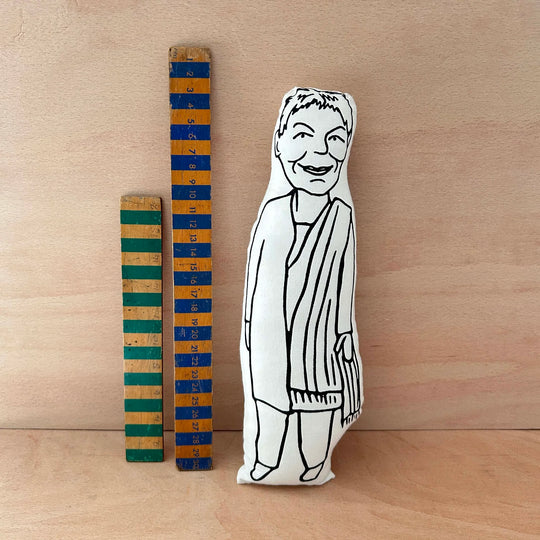 Screen printed doll cushion of Dame Judi Dench next to two wooden rules on a wooden background