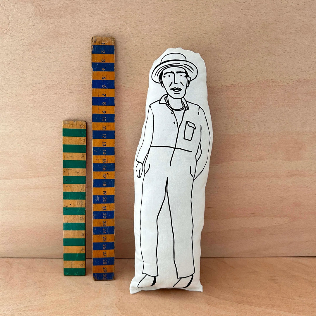 Screen printed doll cushion of Derek Jarman next to two wooden rulers on a wooden background