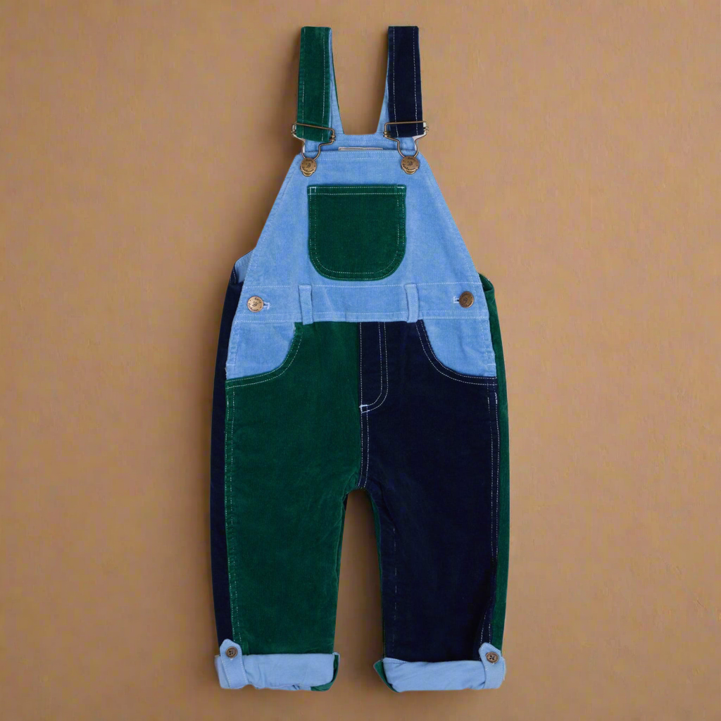 Patchwork corduroy dungarees with pale blue, dark green and dark blue segments and brass buttons