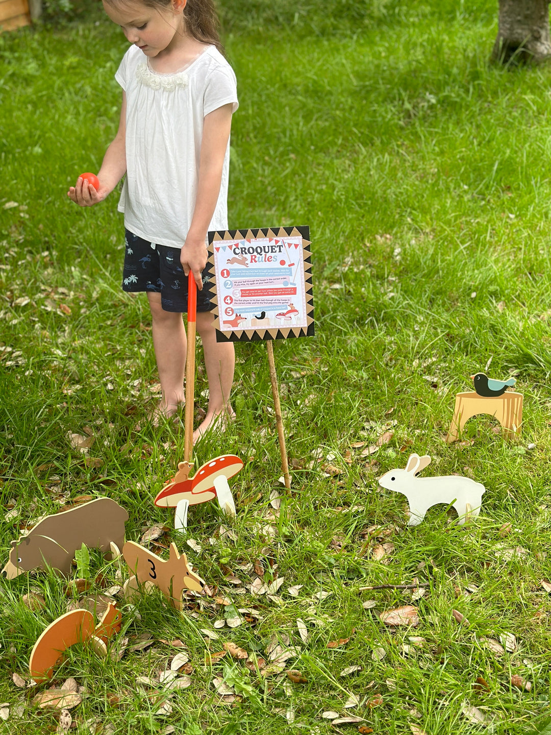 Child playing with a croquet set on grass