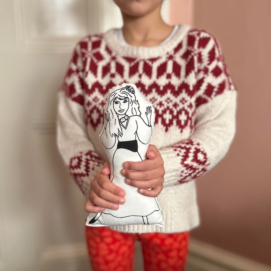 A child holding a black and white screen printed cushion doll with an illustration of singer Kate Bush