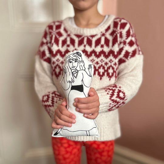 A child holding a black and white screen printed cushion doll with an illustration of singer Kate Bush