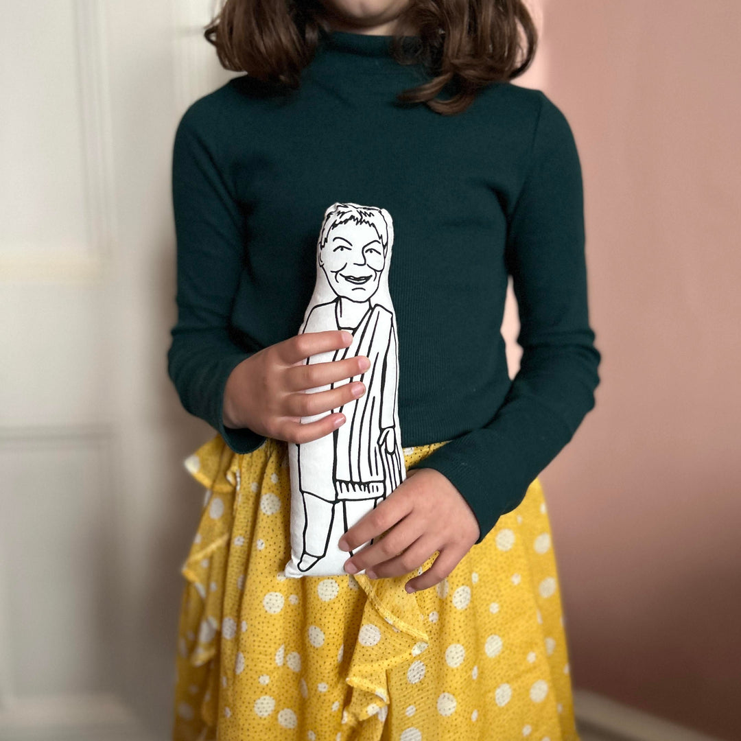 A child holding screen printed doll cushion of Dame Judi Dench