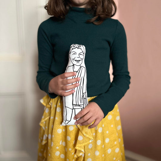 A child holding screen printed doll cushion of Dame Judi Dench