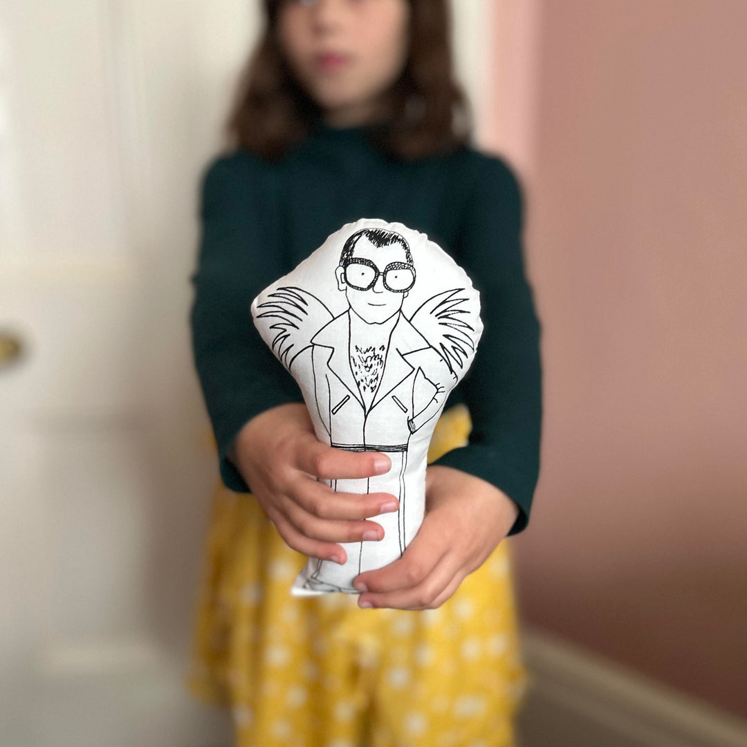 A child holding out the Elton John screen printed doll towards the camera