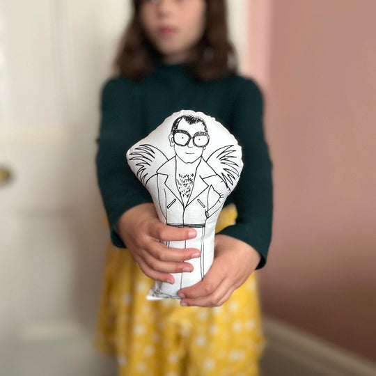 A child holding out the Elton John screen printed doll towards the camera