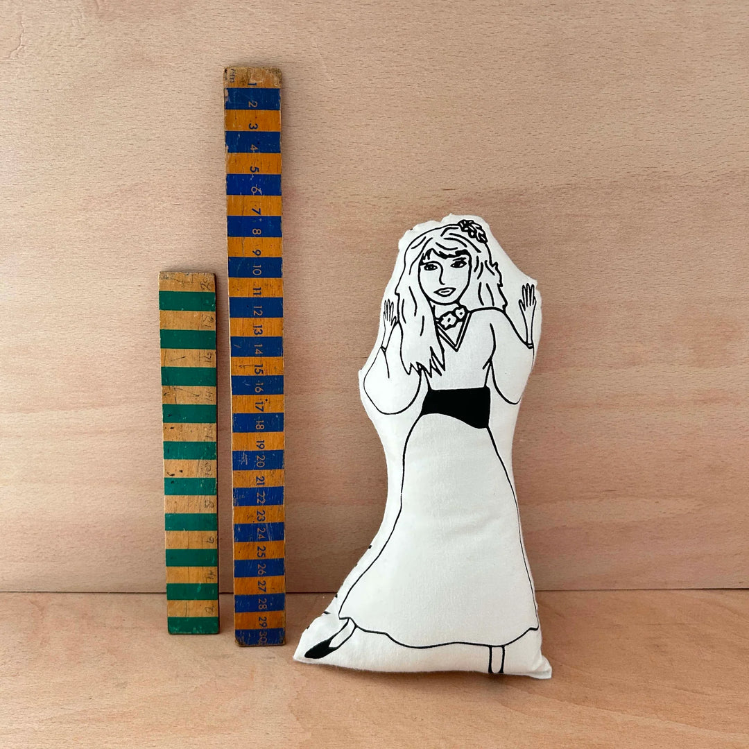 Screen printed doll cushion of Kate Bush next to two wooden rulers on a wooden background