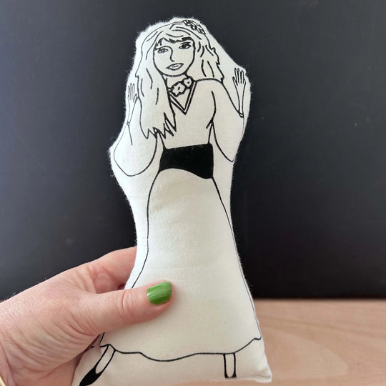 Hand holding screen printed doll cushion with white fabric and black illustration depicting singer Kate Bush dancing in a dress