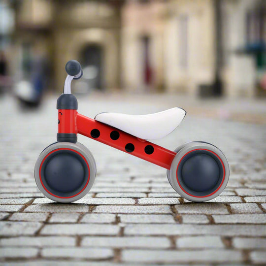 Red and black spots balance bike with grey wheels and white seat side on