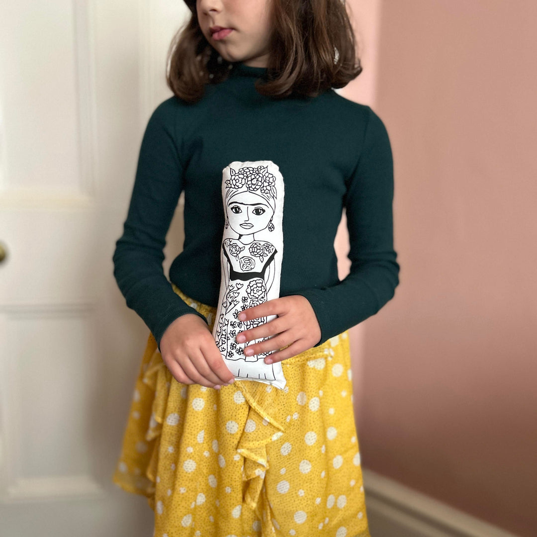 A child holding screen printed doll cushion of Frida Kahlo