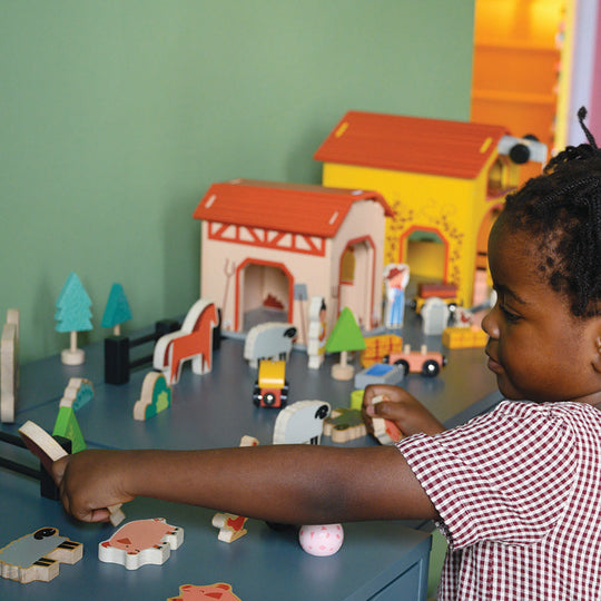 Child playing with toy farm set on a table
